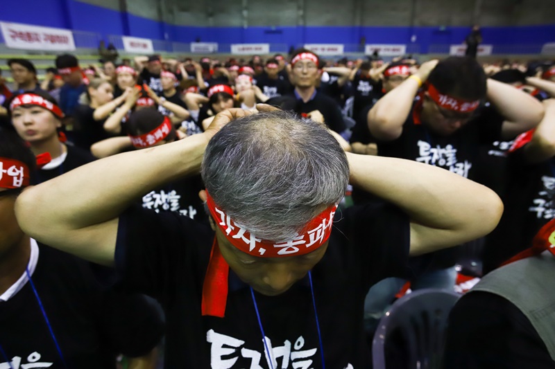 ▲ 민주노총 비상대표자회의에서 참석자들이 총파업을 결의하며 머리띠를 묶고 있다.