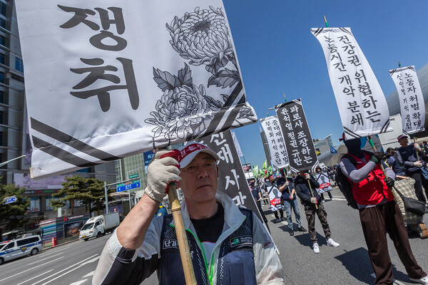 만장을 든 노동자들이 서울시청을 향해 행진하고 있다. 