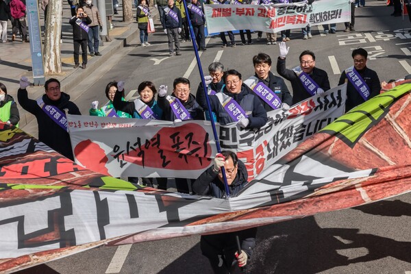 노동자 행진 참가자들이 윤석열 정부 규탄하며 현수막을 찢고 있다.